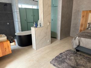 a bathroom with a tub and a bed and a sink at Bandi Manor in Mokopane
