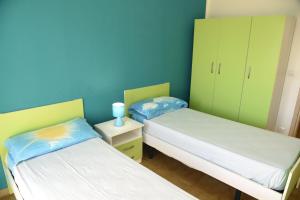 two beds in a room with blue walls and green cabinets at Lungomare Sant'Isidoro 1 in Sant'Isidoro