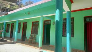 a green building with blue columns in front of it at Tritiya kedar home stay in Rudraprayāg