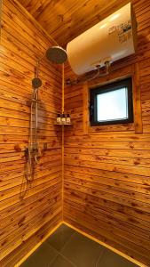 a bathroom with a shower in a wooden wall at MuseNomad Retreat in Honukay