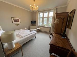 a bedroom with a bed and a table and a chandelier at Hotel & Restaurant Raueneck in Bad Saarow
