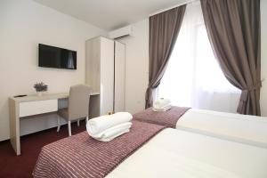 a hotel room with a bed with a desk and a television at Maxim Deluxe Rooms with Balcony & Private Bathrooms - Downtown Spalato, Quiet Neighborhood in Split