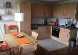 a kitchen with wooden cabinets and a table and a table and chairs at Ferienwohnung Boddenblick in Zudar