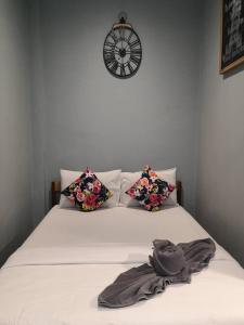 a bed with two pillows and a clock on the wall at Samed Your House Family Room in Ko Samed