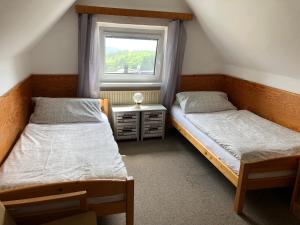 two beds in a room with a window at Penzion Mája Benecko in Benecko