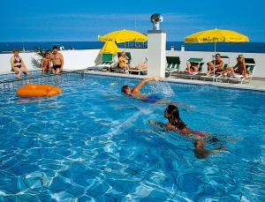 a group of people swimming in a swimming pool at Hotel Nelson in Lido di Jesolo