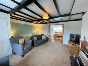 a living room with two blue chairs and a tv at Traditional Cottage with Beautiful Views - Pass the Keys in Isle of Whithorn