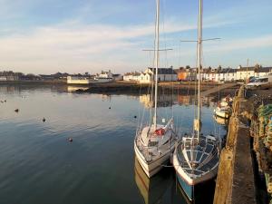 two boats are docked in the water in a harbor at Traditional Cottage with Beautiful Views - Pass the Keys in Isle of Whithorn