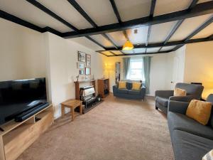 a living room with a couch and a flat screen tv at Traditional Cottage with Beautiful Views - Pass the Keys in Isle of Whithorn +27 photos