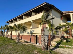a building with palm trees in front of it at home SIKAN casa al mare Licata in Butera