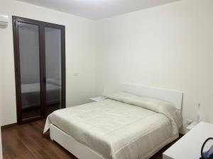 a white bedroom with a bed and a mirror at home SIKAN casa al mare Licata in Butera