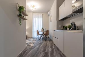 a kitchen with white cabinets and a table with chairs at Suite Da Vinci in Pavia