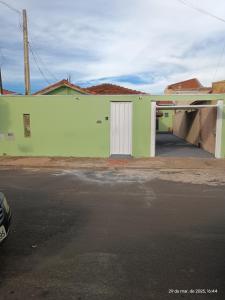 a green building with a white door and a parking lot at RECANTO DA IZAURINHA in Olímpia