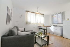a living room with a couch and a table and a kitchen at הדירה בלבן פלאי in H̱adera