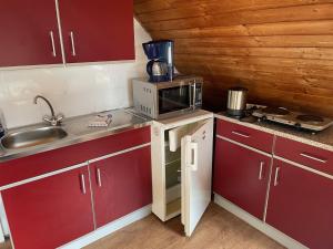 a small kitchen with red cabinets and a microwave at Pension Hesse in Lüdenscheid