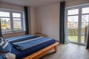 a bedroom with a bed with blue sheets and windows at Ferienwohnungen Zum Fischerhafen in Freest +27 photos