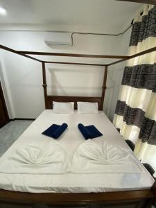 Una cama blanca con dos almohadas azules encima. en Minsil Villa, en Hikkaduwa