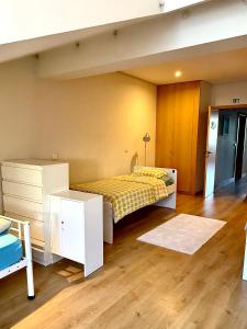 a bedroom with a bed with a yellow bedspread and a wooden floor at Âmbar Guest House in Braga