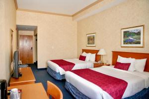 a hotel room with two beds and a desk at The Glengate Hotel & Suites in Niagara Falls