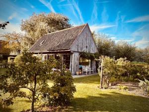 an old barn in a yard with a tree at De Zonnebrug in Sint-Laureins