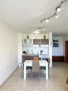 a kitchen and dining room with a white table and chairs at К-с Сън Коуст in Sveti Vlas