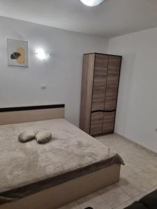 a bedroom with a bed and a wooden cabinet at К-с Сън Коуст in Sveti Vlas