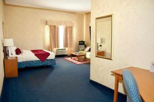 a hotel room with a bed and a mirror at The Glengate Hotel & Suites in Niagara Falls