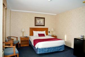 a hotel room with a bed and a chair at The Glengate Hotel & Suites in Niagara Falls