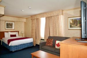 a hotel room with a bed and a couch at The Glengate Hotel & Suites in Niagara Falls