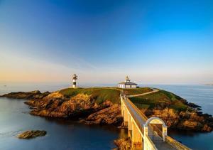 un pont menant à un phare dans l'océan dans l'établissement Apartamento AIIA, à Ribadeo 5 autres photos