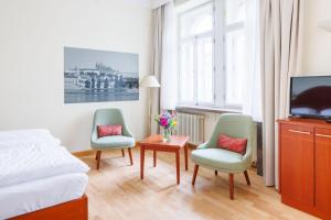 1 Schlafzimmer mit 2 Stühlen, einem TV und einem Bett in der Unterkunft Hapimag Apartments Prague in Prag