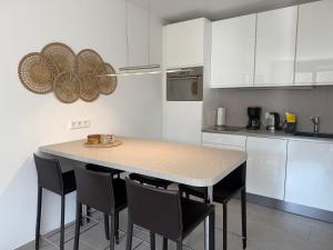 a kitchen with a table with chairs and white cabinets at Ferienwohnung Meerzeit Mardorf in Neustadt am Rübenberge