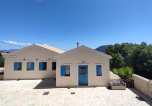 a white house with a blue door on a driveway at Villa Sasà in Fiskardo