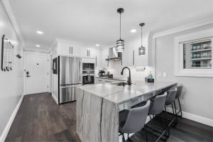 a white kitchen with a large island in the middle at Modern Escape - Luxury Oceanfront Views with Pool, Parking and Amenities in Myrtle Beach