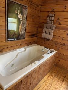 a bath tub in a wooden bathroom with a deer picture at Log Cabin in Bailey Camp