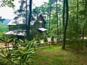 a house in the woods with a fence and trees at Log Cabin in Bailey Camp