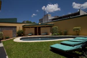 a pool with green lounge chairs next to a building at Corrientes Plaza Hotel in Corrientes