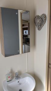 a bathroom with a white sink and a mirror at Floppy Feet Pet Friendly Holiday Home Thornwick Bay, Flamborough in Flamborough