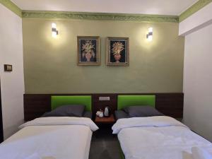 two beds in a room with green walls at D GAYA HOTEL Cameron Highlands in Tanah Rata