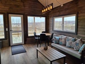a living room with a couch and a table and windows at Country cottage in Þingeyjarsveit