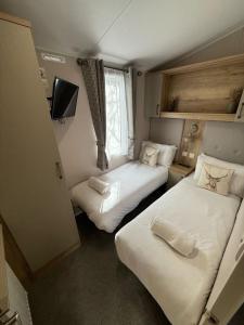 a small room with two beds and a television at Cuckoo Lodge with Hot Tub at Brickyard Lakes in Amotherby