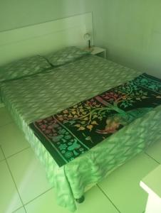 a bed with a green comforter on top of it at La Casa del Monica in Itacaré