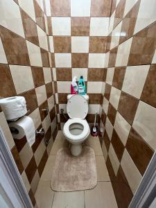 a bathroom with a toilet and a checkerboard wall at Urban oasis in Port Louis