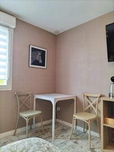 a room with a table and two chairs and a tv at La Maison au bord de Saône in Pagny-la-Ville
