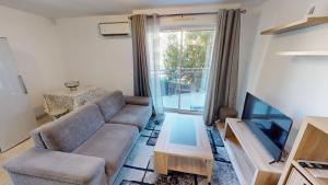 a living room with a couch and a tv at Superbe T2 refait à neuf avec balcon vue montagne à un arrêt de Monaco in Roquebrune-Cap-Martin