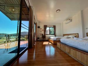 a bedroom with two beds and a large window at Mae Klang Luang Villa แม่กลางหลวงวิลล่า in Ban Sop Mae Klang