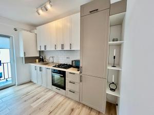 a kitchen with white cabinets and a wooden floor at Bucovina Home Apartament in Gura Humorului