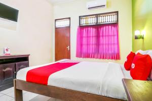 a bedroom with a bed with a red and white blanket at OYO 2184 Nan Berlian Inn in Legian