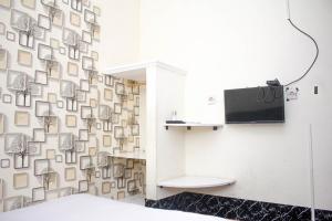 a room with a wall covered in photographs at Capital O 2258 Santana Syariah Guest House in Solo +19 photos