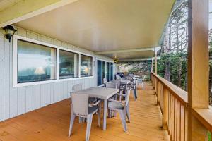 a porch with tables and chairs and windows at Falcon's Nest in Twin Rocks